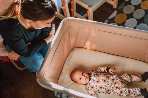 Free A mother lovingly watches over her baby in a crib from an overhead view. Stock Photo