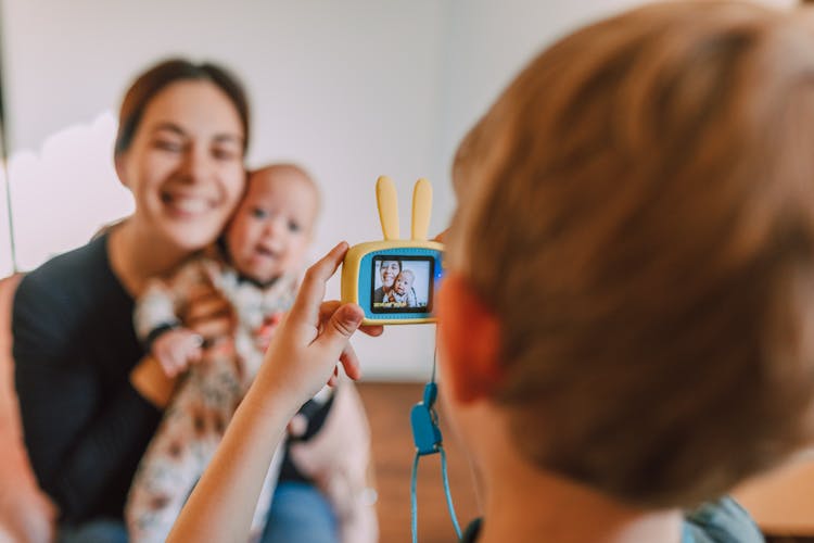 A Child Taking A Picture Of A Mother And A Baby