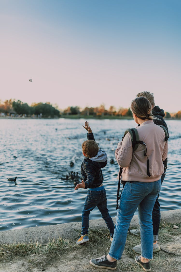 A Child Throwing A Stone In Body Of Water