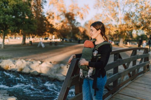 Free A serene moment of a mother and baby on a wooden bridge in an autumn park. Stock Photo