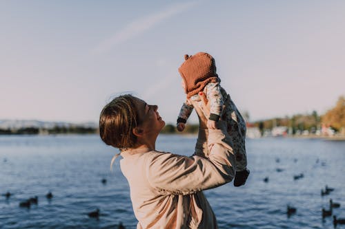 Woman Carrying Her Baby Near a Lake