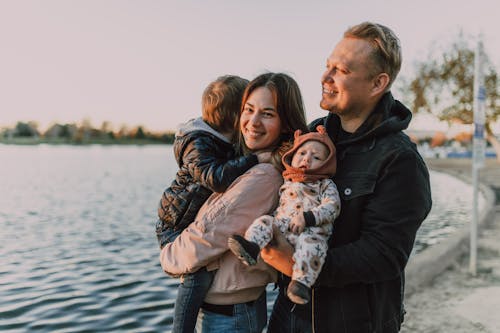 Free A Couple with a Child and Baby Standing Near a Lake
 Stock Photo