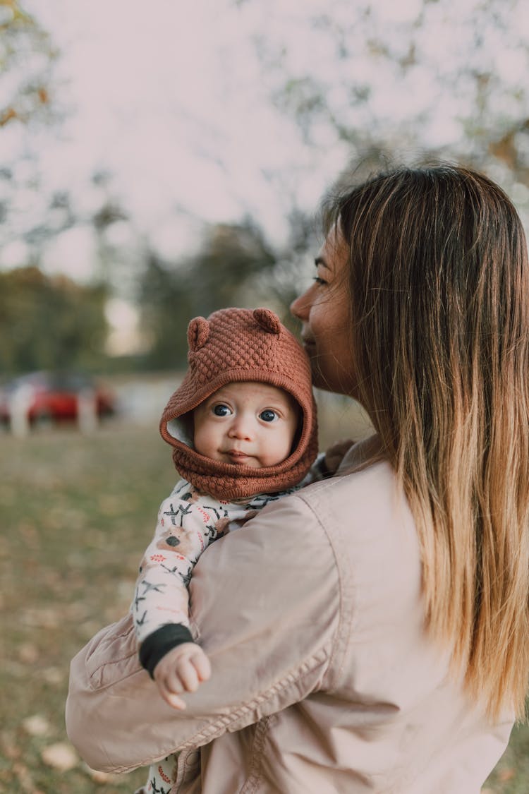 A Mother Carrying Her Baby With A Knit Cap