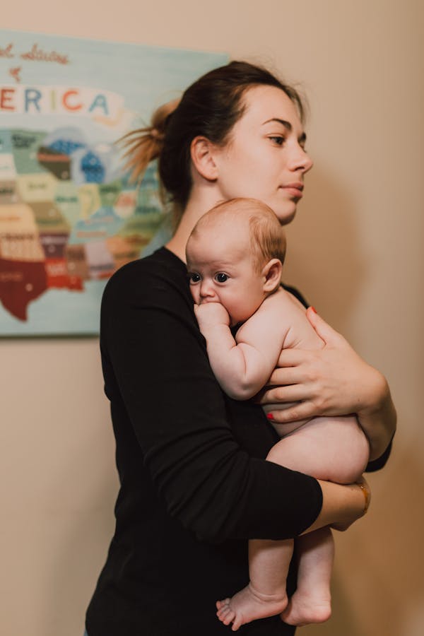 Woman in Black Long Sleeve Shirt Carrying Baby