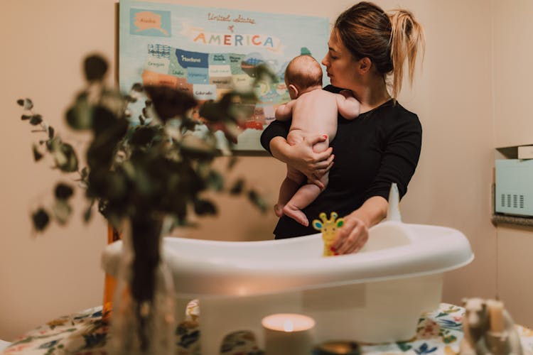 A Mother Bathing Her Baby In A Basin