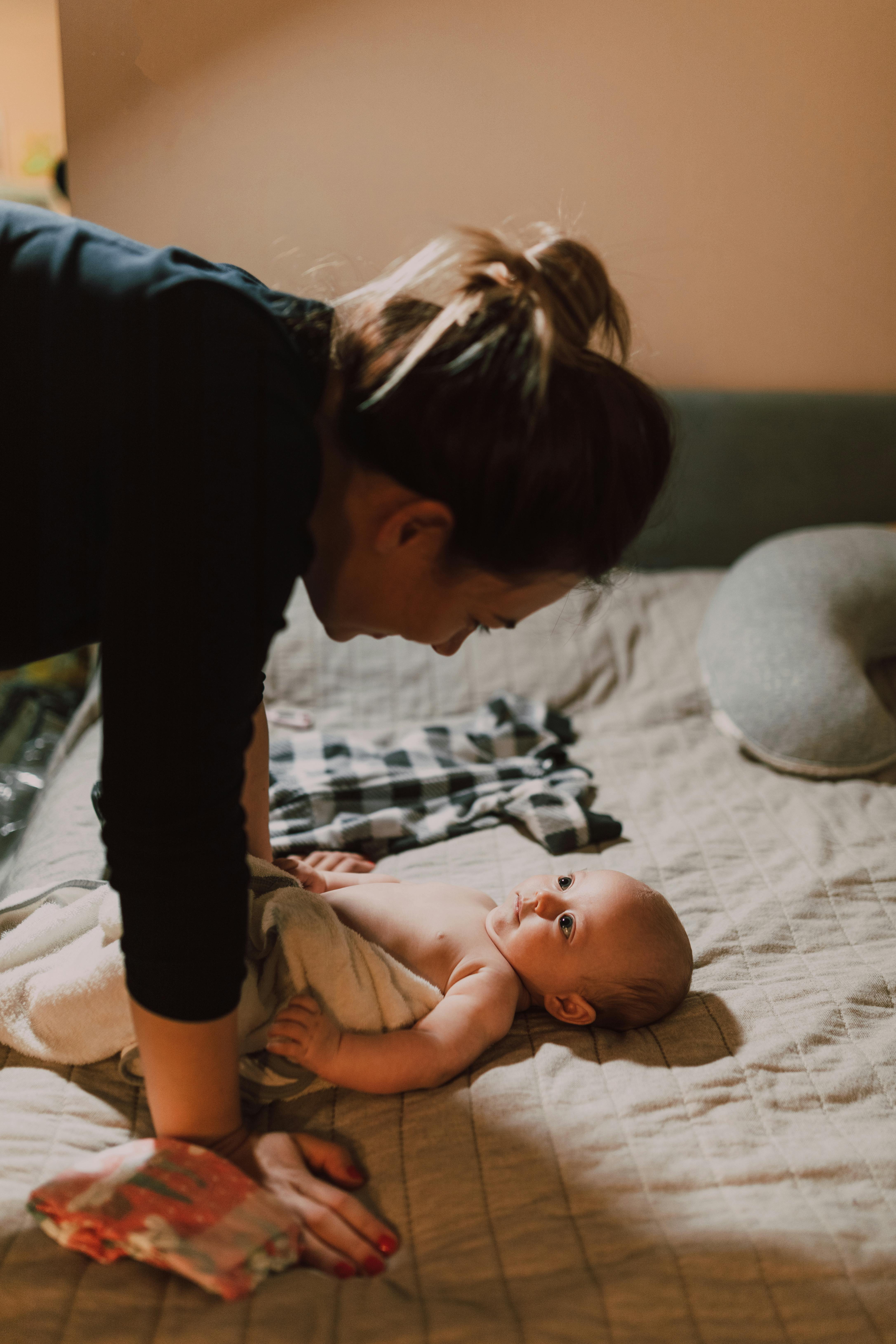 woman in black long sleeve shirt holding baby in white onesie