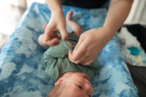 A Person Fixing the Baby's Clothes 