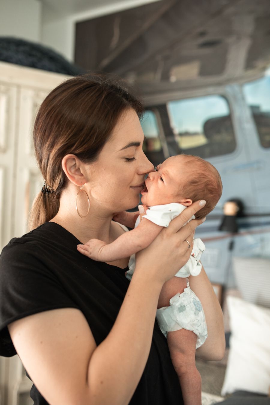 Mother gently holding her newborn baby indoors after birth