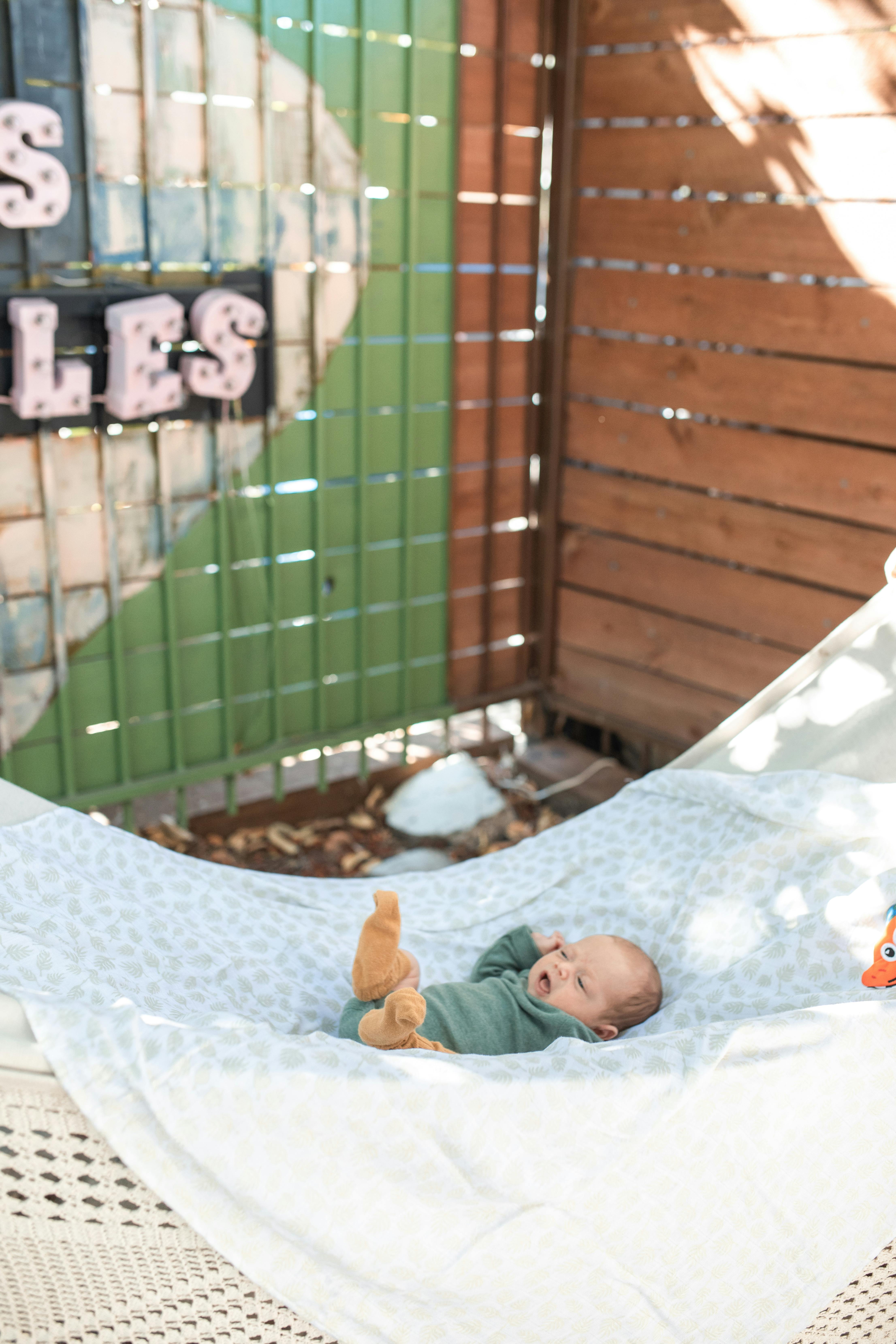 baby in orange jacket lying on white textile