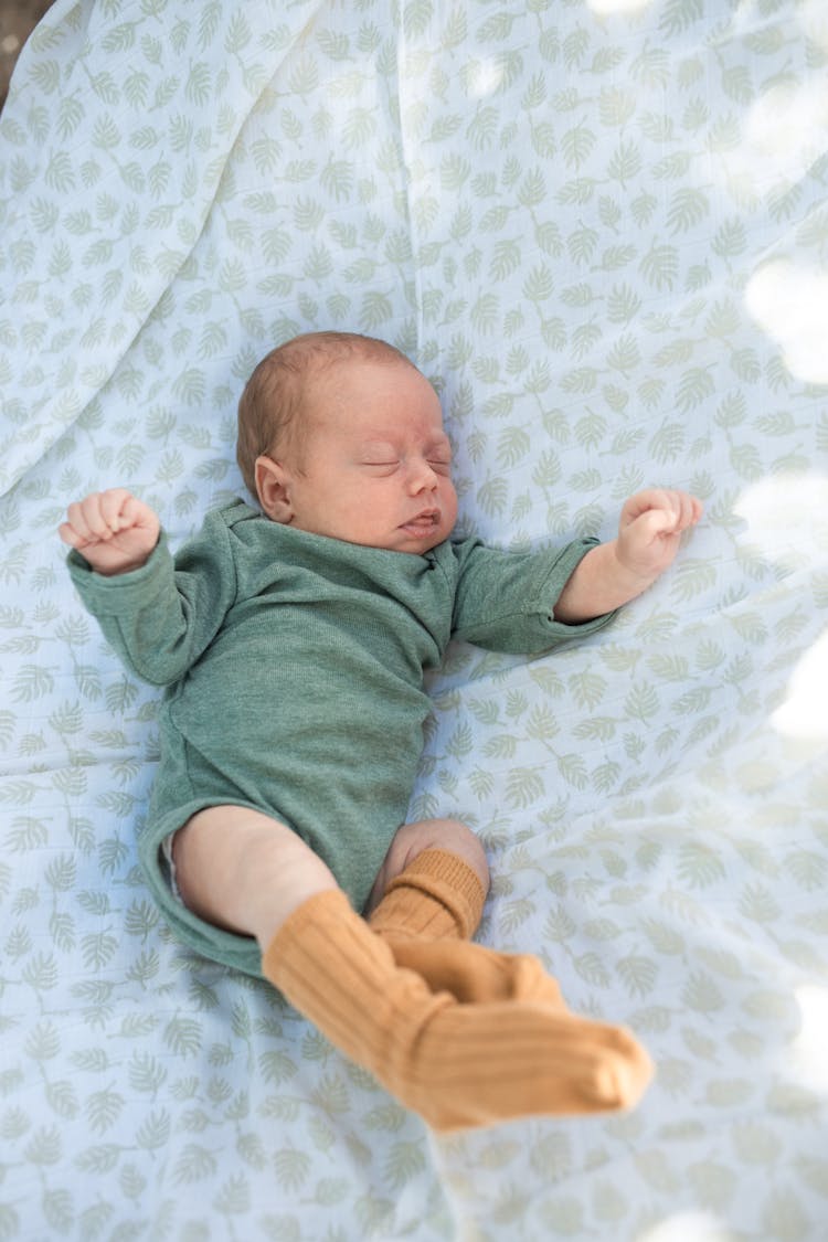 A Newborn Baby In Onesie Sleeping