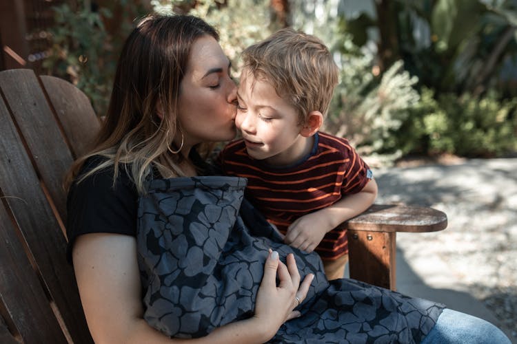 Woman Holding A Baby And Kissing Her Elder Son