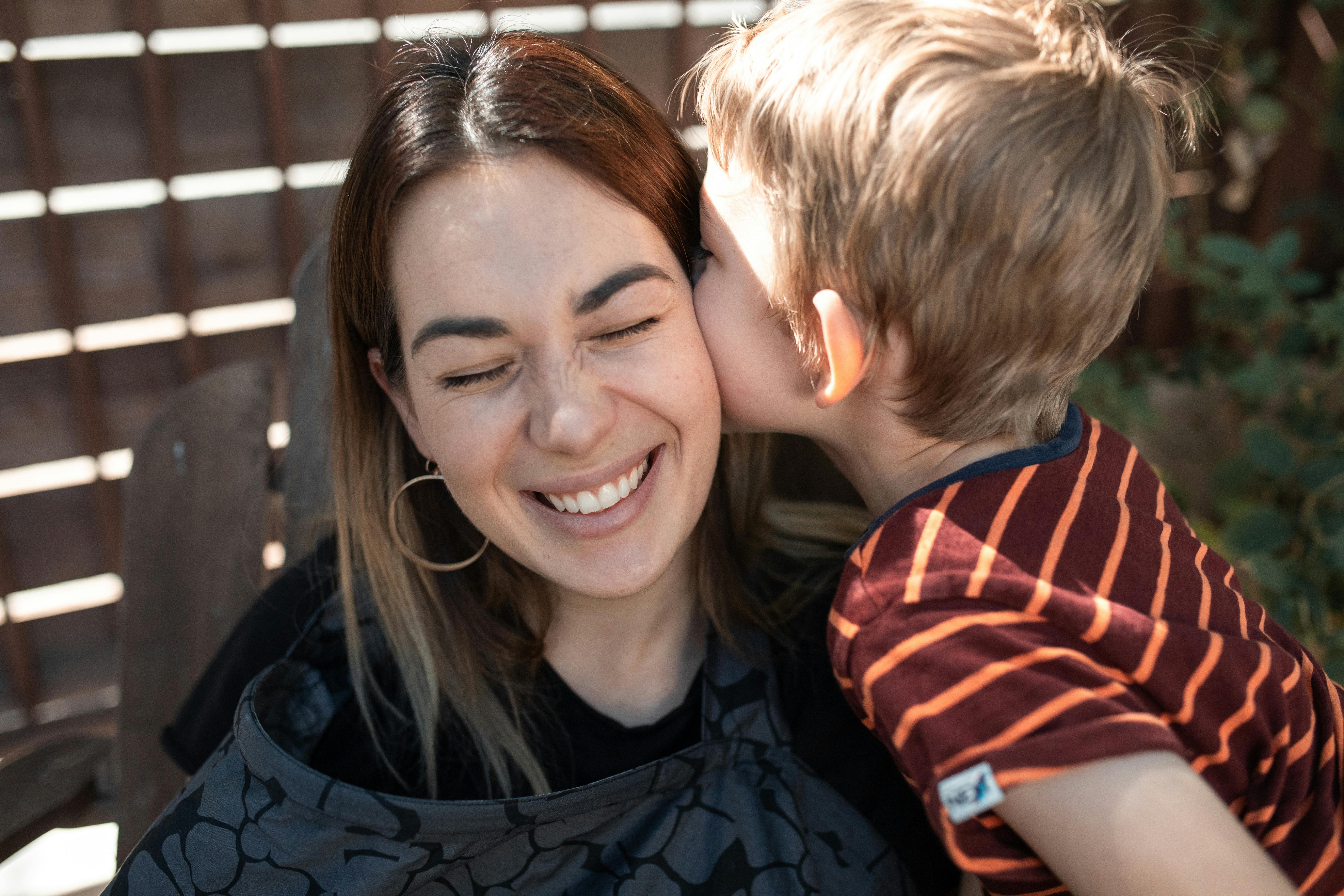 woman in black and red striped shirt smiling beside boy in blue and red striped shirt