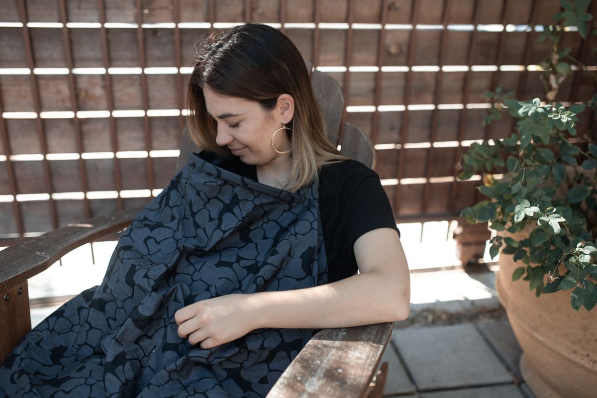 Mother breastfeeding her baby outdoors with a nursing cover