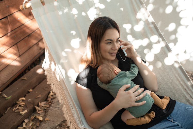 A Mother Having A Phone Call While Carrying A Baby