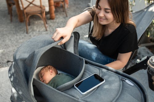 Free Woman Looking at Her Baby in a Stroller Stock Photo