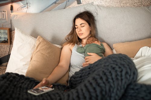 Free A Woman Resting on the Bed with Her Baby on Top Stock Photo