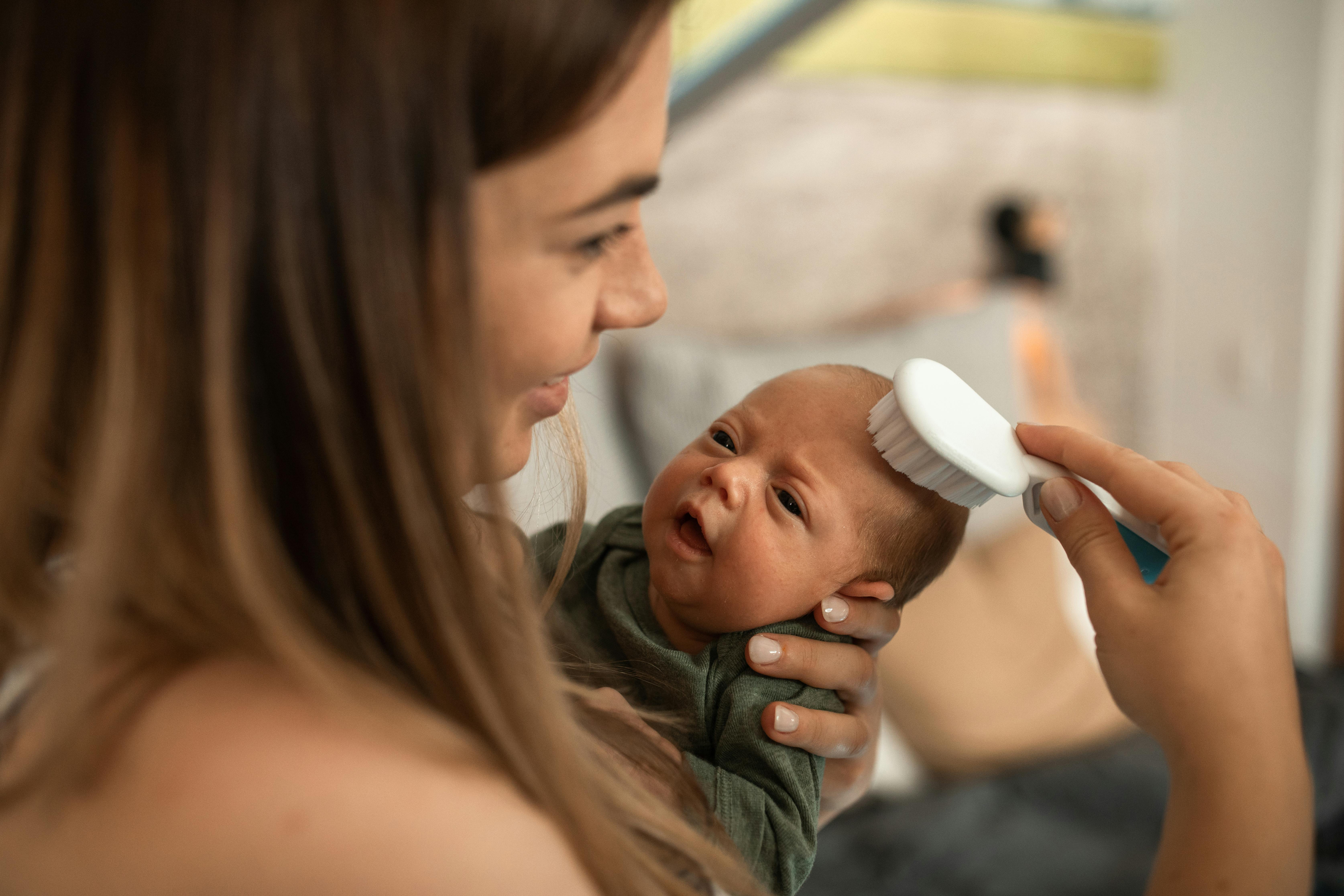 a woman carrying her newborn baby while brushing hair