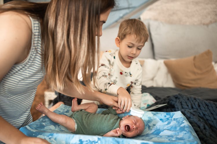 A Mother And Son Brushing The Baby's Hair