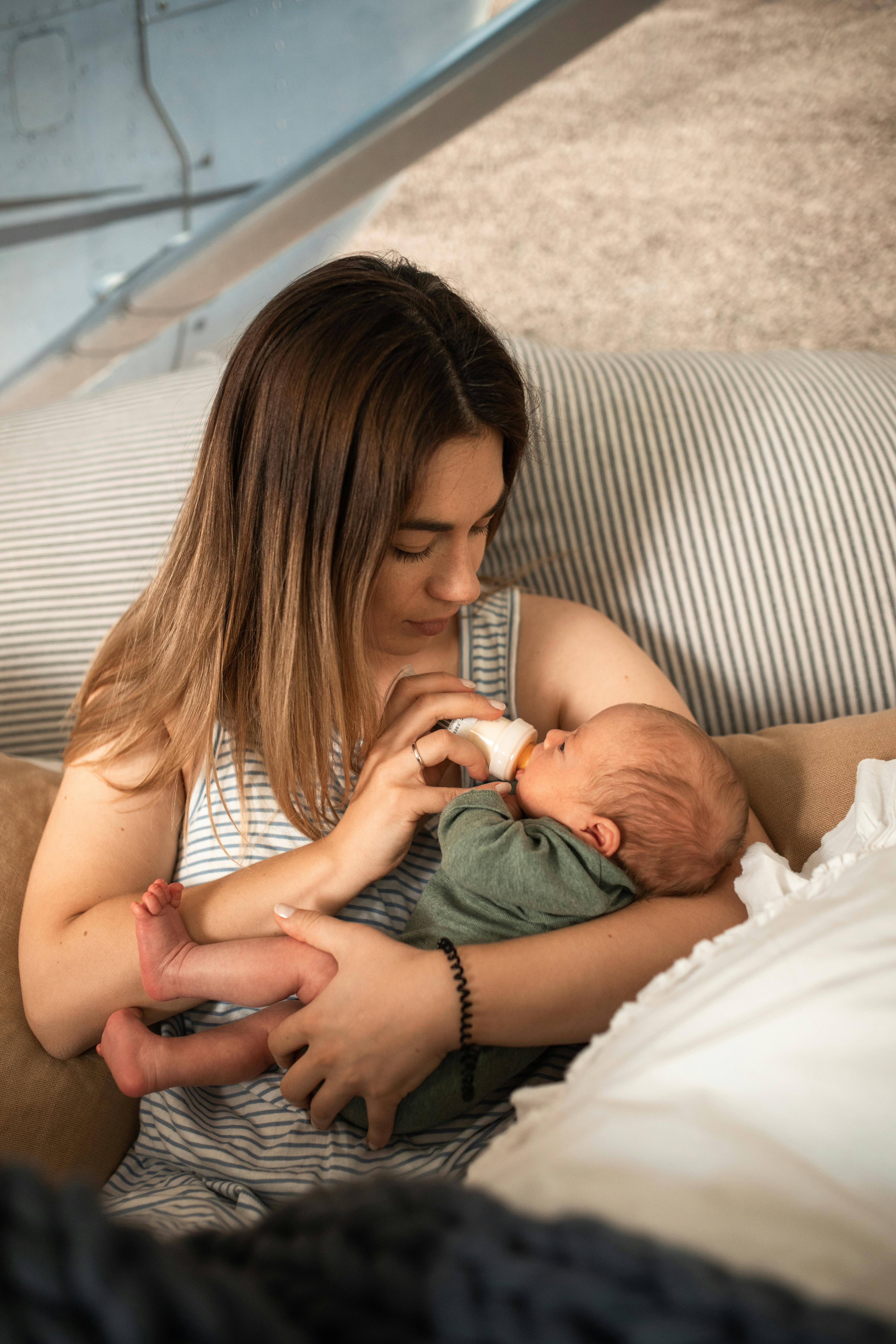 a woman feeding her baby using milk bottle
