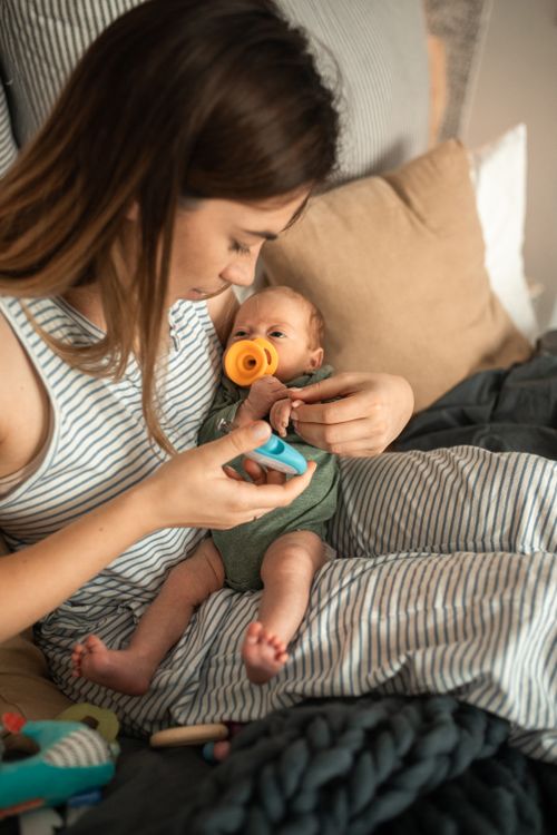 Free A mother lovingly holds her newborn baby indoors, showcasing warmth and connectedness. Stock Photo