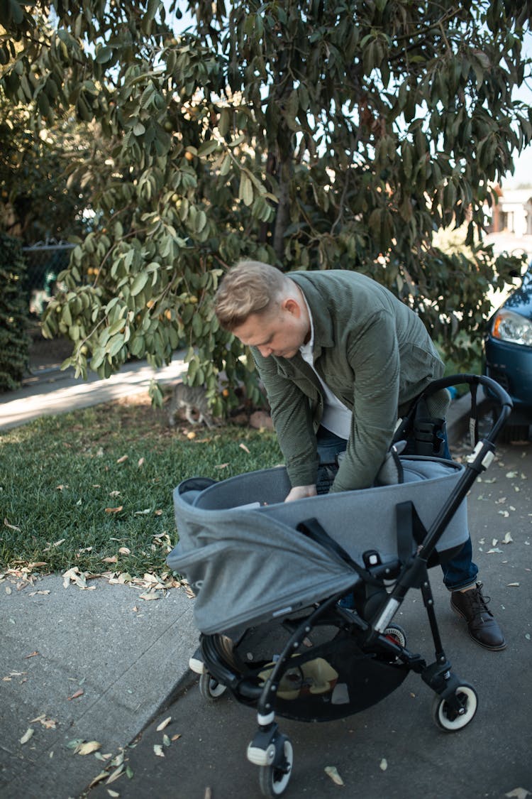 A Man Reaching For The Baby On A Stroller