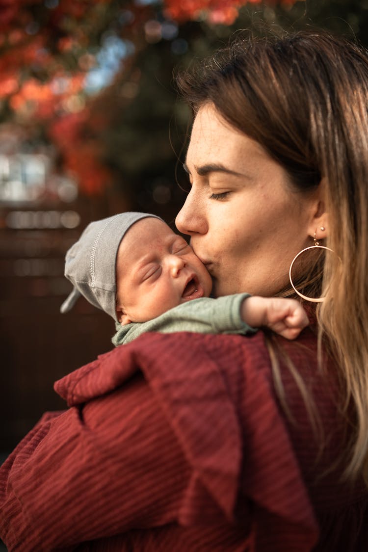 A Mother Kissing A Newborn Baby