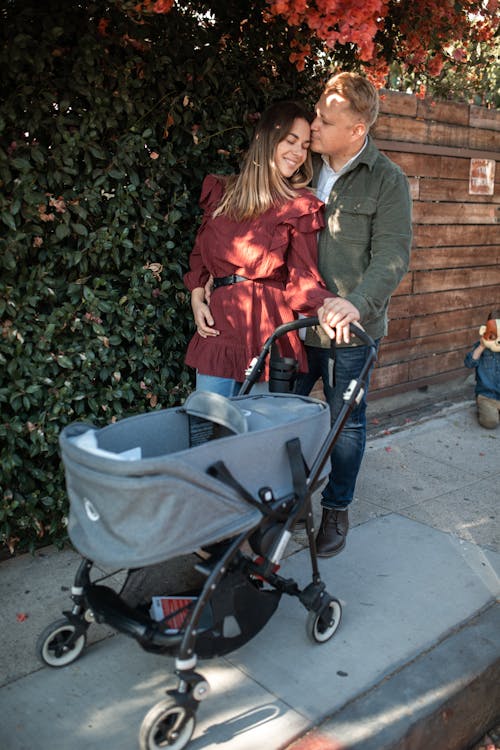 Woman in Red Jacket and Gray Pants Sitting on Black Stroller