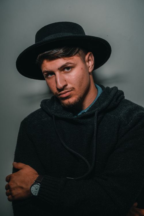 Free Portrait of a confident man wearing a fedora hat and hoodie, exuding style and charisma. Stock Photo