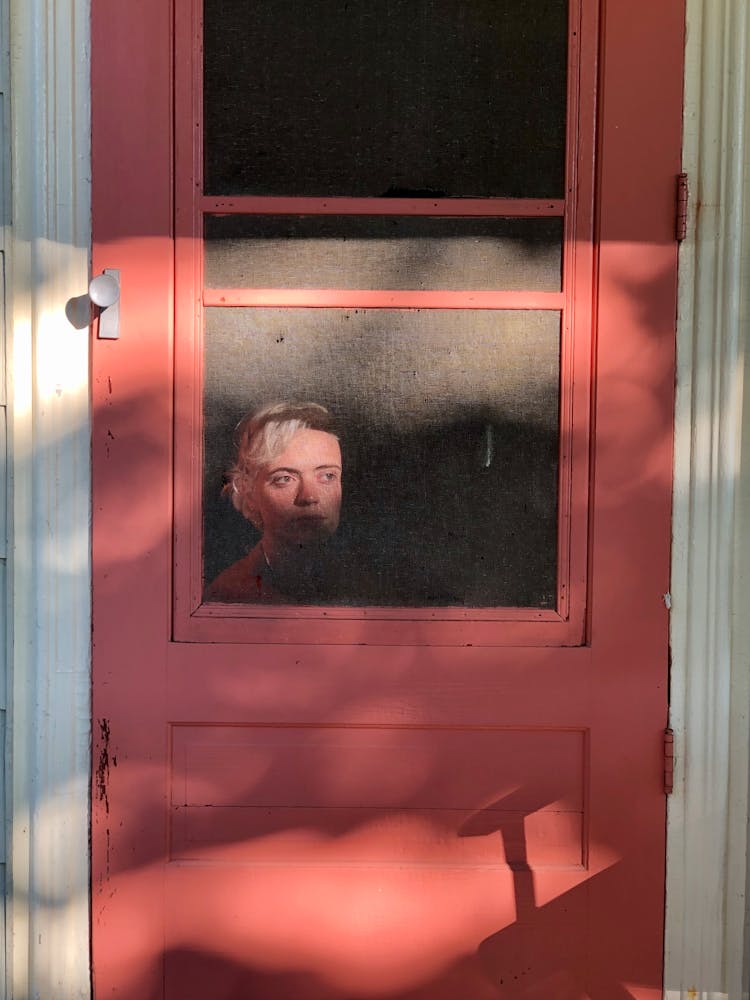 Young Woman Sitting Behind Cottage Door And Looking Away