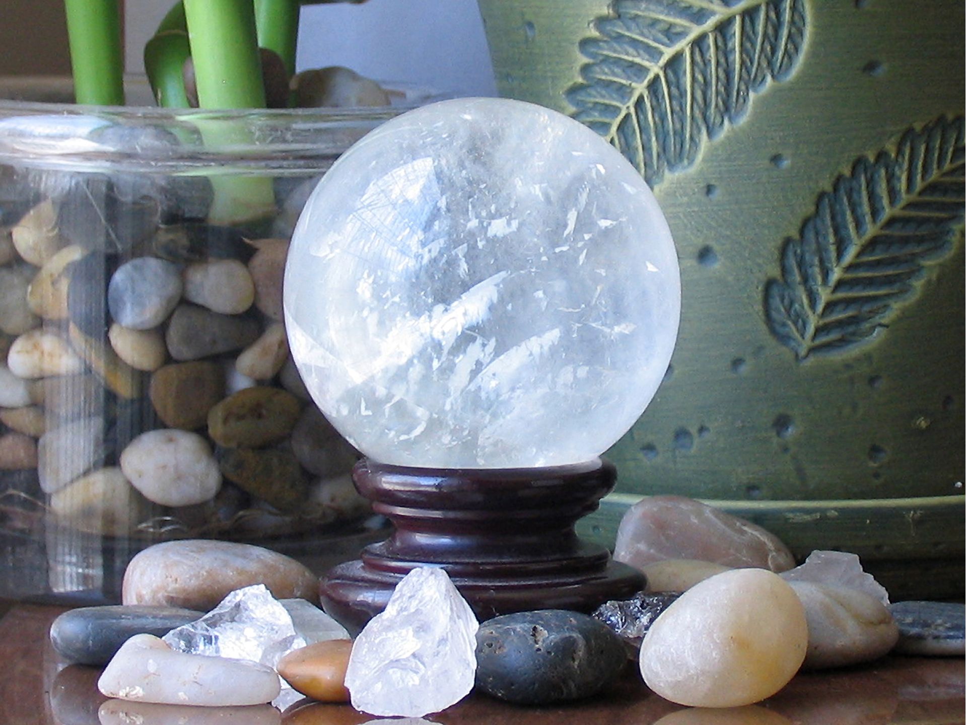 Intriguing still life of a crystal ball with stones and a decorative plant, perfect for home decor themes.