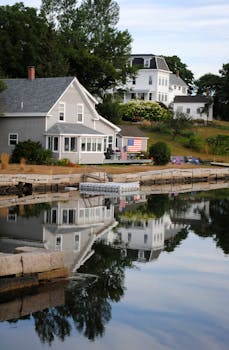 Contemporary residential cottages with USA flags on facades located on peaceful lake shore in summer countryside