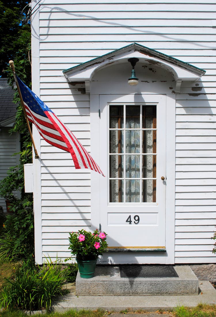 American Flag Waving Near Door Of White Residential House