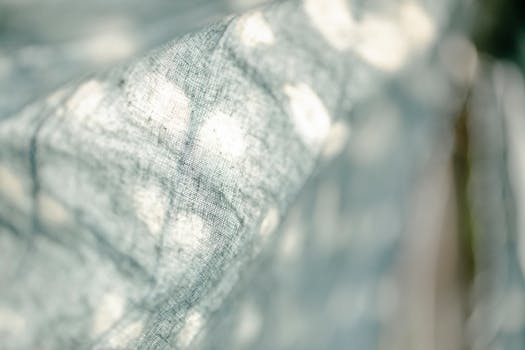 Closeup of light dyed textile with white spots hanging on street with green plants on blurred background in sunny weather