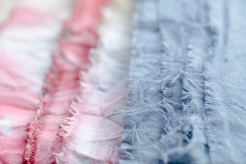 Blue and pink textile with threads placed on surface in modern professional studio on blurred background during production of clothes