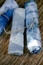 From above rolls of colorful dyed fabric with creative design tied with ropes placed on wooden surface in modern workshop