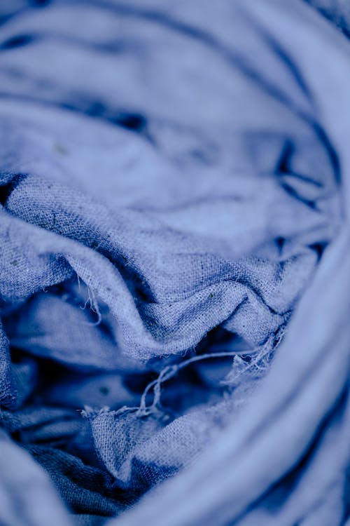 From above of crumpled blue dyed textile placed on table in modern professional workshop during production of fabric on blurred background