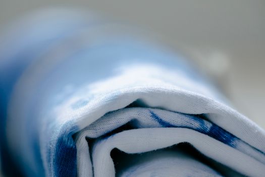 Closeup roll of colorful dyed fabric with white ad blue spots placed against blurred background in modern studio during production of textile