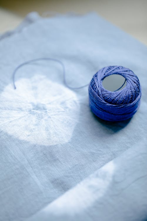 Free From above of blue yarn placed on fabric with creative round pattern in professional light studio using modern shibori dyeing technique Stock Photo