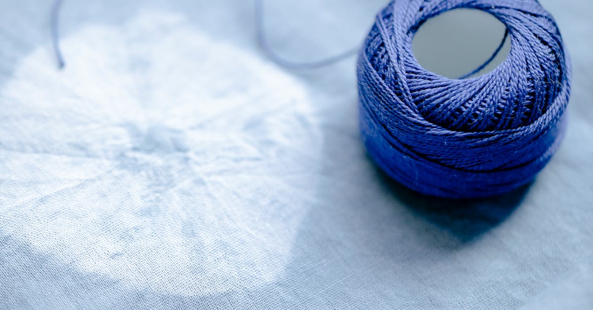 From above of blue yarn placed on fabric with creative round pattern in professional light studio