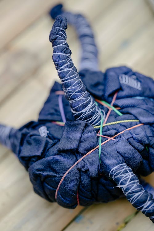 From above of blue textile tied with threads after shibori dyeing placed on wooden surface on blurred background in workshop