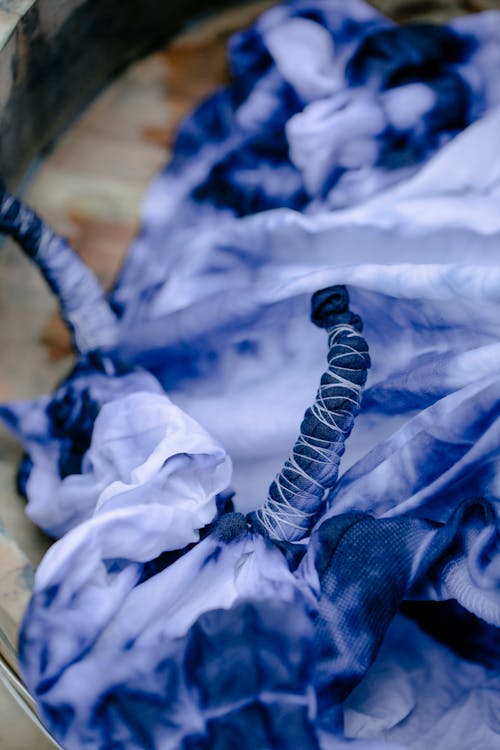 Free From above of colorful tied fabric with creative white spots dyed using shibori technique placed on surface in professional workshop Stock Photo
