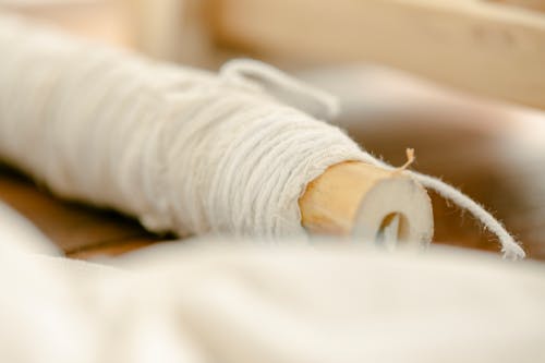 Thread reeled on wooden stick placed on wooden table on blurred background in light room