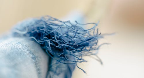 Closeup of colorful loosen threads of natural blue textile hung on clothesline on blurred background