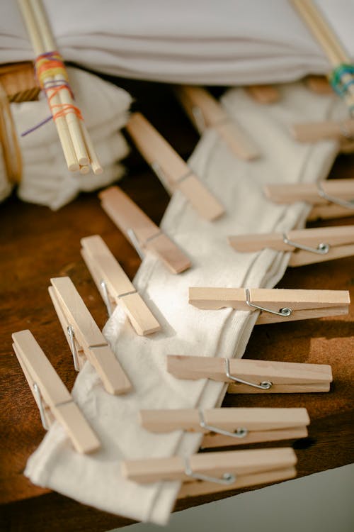 From above of wooden clothespins on table with sticks for weaving tied with multicolored threads and natural fabric