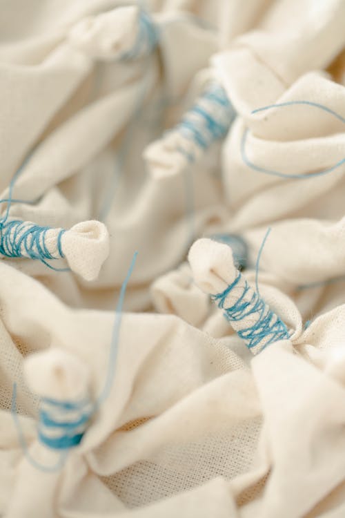 From above of white cotton cloth tighten with thin blue threads on blurred background