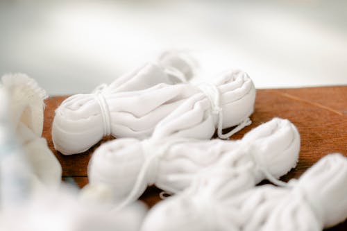 From above set of tied white cotton fabrics placed on wooden table in atelier before tie dyeing in shibori technique