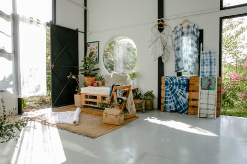 Free Interior of minimalist spacious atelier with various hanging tie dyed clothes and wooden furniture decorated with assorted fresh potted plants Stock Photo