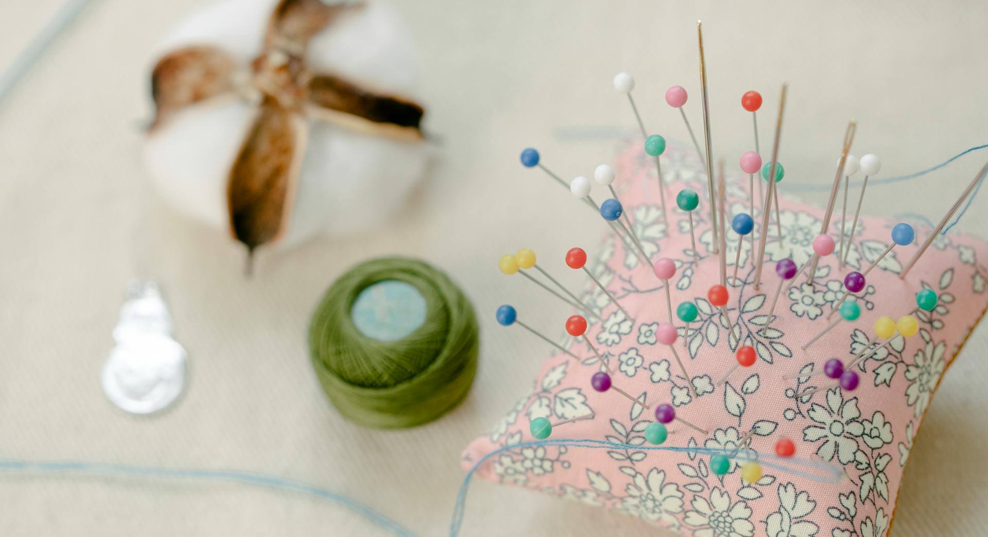 Needle pillow with pins placed on table with thread spool