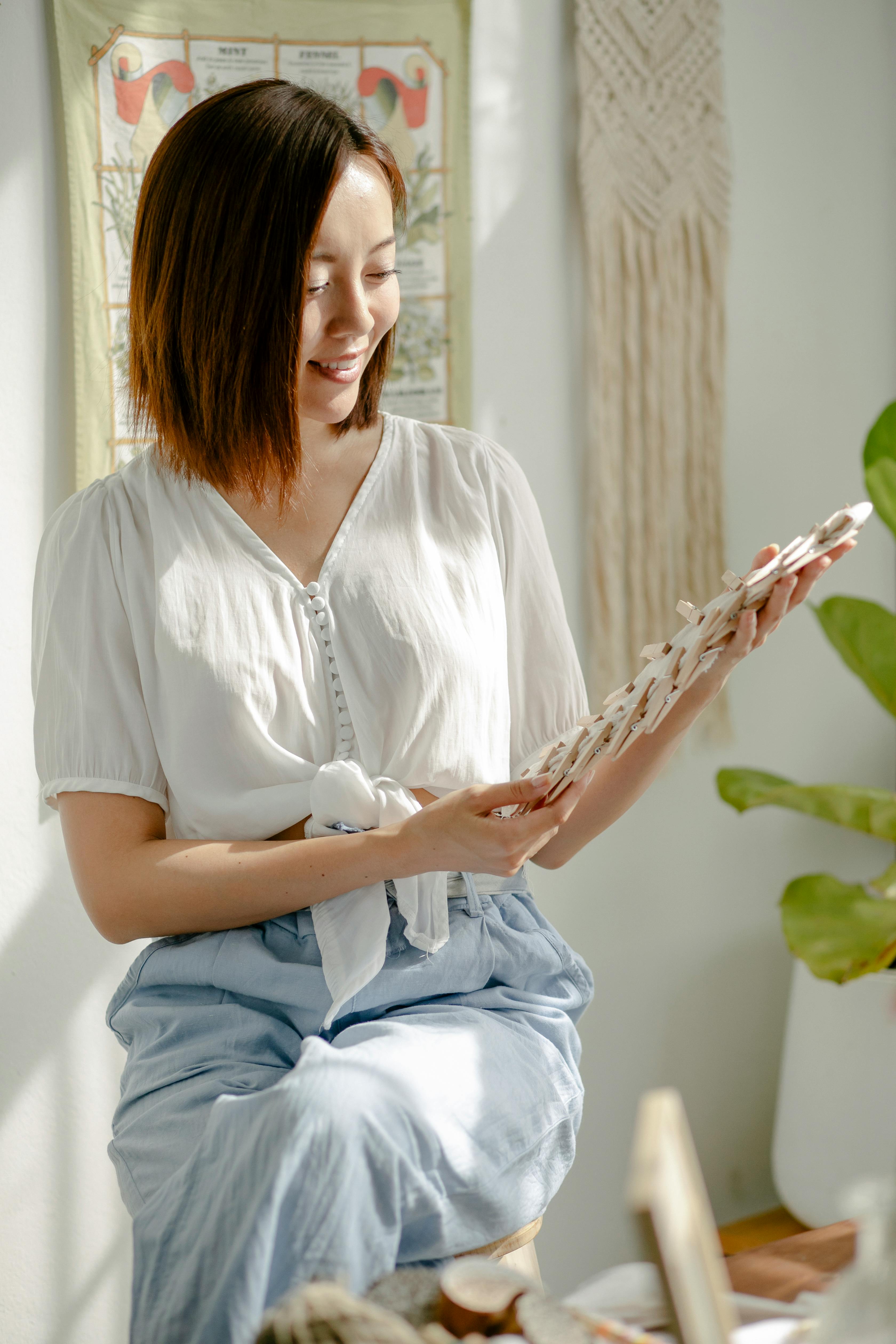 Smiling young female master holding tools during dying fabric in shibori technique
