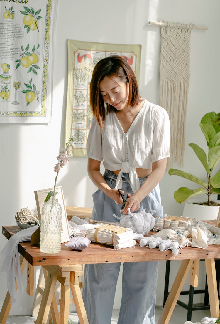 Young Asian Craftswoman Cutting Tied Clothes In Modern Shibori Workshop